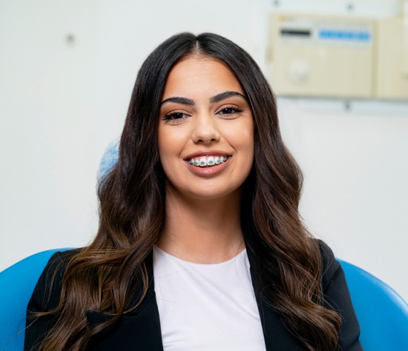 Young woman smiling with metal braces at a dental clinic in Houston, TX