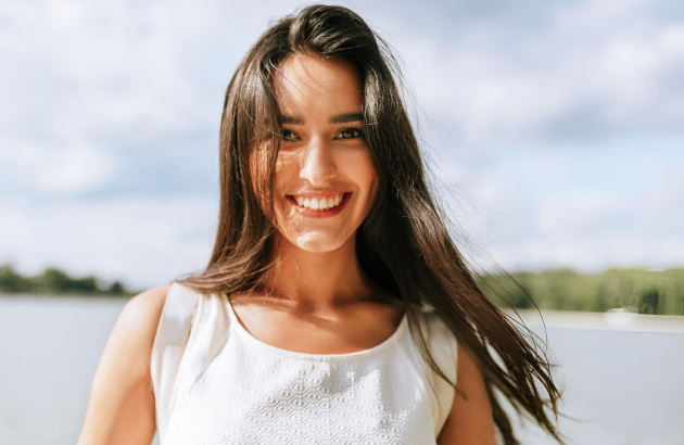 Smiling woman shows natural, even teeth after cosmetic dental bonding in Houston